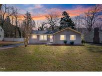 Charming single-story home with a well-maintained lawn, inviting curb appeal, and colorful sunset at 205 Coachman Dr, Garner, NC 27529