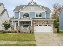 Two-story house with blue siding, stone accents, and a two-car garage at 325 Quarryrock Rd, Holly Springs, NC 27540