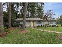 Gray house with yellow door, stone path, and mature trees at 3616 Colewood Dr, Raleigh, NC 27604