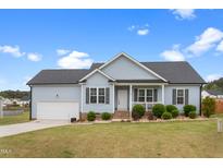 Charming single-story home featuring a well-manicured lawn, attached garage, and inviting front porch at 58 Northview Dr, Middlesex, NC 27557