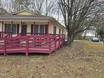 Ranch home with ramp access, maroon railings and mature trees at 1102 E Ellerbee St, Durham, NC 27704