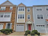 Three-story townhome with stone and siding, two-car garage, and landscaping at 1527 Haywards Heath Ln, Apex, NC 27502