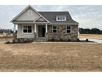 Charming single-Gathering home showcasing stone accents, dormer window, and a covered front porch at 292 Weddington Way, Benson, NC 27504