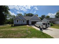 Charming single-story home with light blue siding and an attached garage on a sunny day at 121 Tanglewood Dr # 8-J, Louisburg, NC 27549