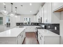 Modern kitchen featuring white cabinets, a kitchen island, stainless steel appliances, and stylish backsplash at 602 Hillfarm Dr, Wake Forest, NC 27587