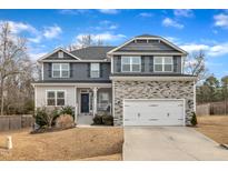 Charming two-story home features a stone and gray facade, well-manicured lawn, and an attached two-car garage at 298 Hannah Yam Ln, Benson, NC 27504