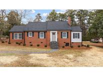 Brick ranch home with gray door, stone steps, and landscaped yard at 103 Park Dr, Oxford, NC 27565