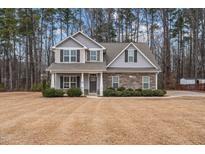 Two-story house with gray siding, stone accents, and a landscaped lawn at 116 Saddle Ln, Lillington, NC 27546