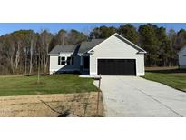 Newly constructed home with a gray exterior, black garage door, and a well-manicured lawn at 120 Magnolia Run Way, Benson, NC 27504