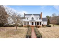 Stately two-story white home featuring a brick walkway, grand front porch, and lush, landscaped grounds at 1200 Spring Valley Lake Rd, Henderson, NC 27536