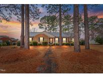 Brick ranch home with walkway, landscaping, and mature trees at 302 S Pine St, Benson, NC 27504