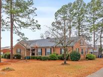 Charming single-story brick home featuring mature trees and lush landscaping, creating a serene and inviting curb appeal at 302 S Pine St, Benson, NC 27504