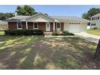 Charming brick home features a well-manicured lawn and an attached two-car garage at 307 Westfield Dr, Dunn, NC 28334