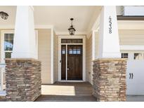 Charming entryway with a dark wood door, stone accents, and craftsman-style columns at 4538 Brighton Ridge Dr, Apex, NC 27539