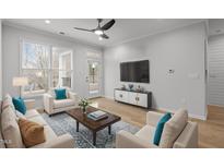 Bright living room featuring light wood floors, a ceiling fan, and ample natural light from large windows at 105 Fountain Ridge Pl, Holly Springs, NC 27540