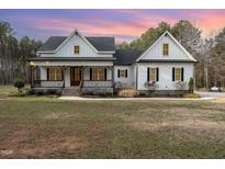 White farmhouse exterior boasts a welcoming front porch and expansive lawn at 95 Somerset Ln, Henderson, NC 27537