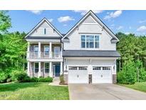 Two-story house with white siding, stone accents, and a two-car garage at 1305 Magnolia Glen Circle, Wake Forest, NC 27587