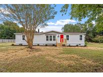Newly renovated mobile home with gray siding and red door, situated on a spacious lot at 262 Homestead Dr, Selma, NC 27576