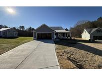 Newly constructed home with gray siding, a two-car garage, and a concrete driveway at 411 Magnolia Run Way, Benson, NC 27504