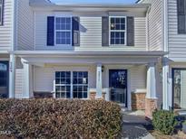 Beige two-story townhome with a covered porch and landscaping at 5211 Blue Lagoon Ln, Raleigh, NC 27610