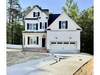 New construction two-story home featuring white siding, black shutters, and a two-car garage with a paved driveway at 2628 Silver Gate Ct, Wake Forest, NC 27587