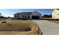 Newly constructed home with a beige exterior, dark brown garage door, and landscaping at 44 Wynd Crest Way, Benson, NC 27504