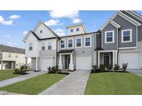 Charming townhome exteriors with a combination of siding, stone accents, and individual garages on a manicured lawn at 556 Eversden Dr, Zebulon, NC 27597