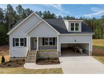 Charming craftsman-style home featuring a stone facade, covered porch, and attached garage in a serene wooded setting at 95 Purslane Dr, Franklinton, NC 27525