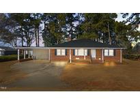 Charming brick home with a covered carport, a well-manicured lawn, and mature trees at 205 N Augusta Ave, Benson, NC 27504