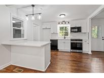 Bright kitchen features white cabinets, modern appliances, stylish backsplash, and beautiful hardwood floors at 3907 Inwood Dr, Durham, NC 27705