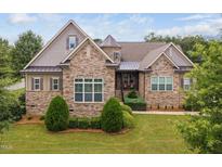 Stone and shingle exterior of a two-story home with manicured landscaping at 7440 Bleasdale Ct, Apex, NC 27539
