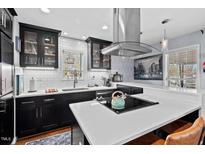 Modern kitchen featuring black cabinets, white subway tile, and stainless steel appliances and range hood at 1801 Liberty St, Durham, NC 27703