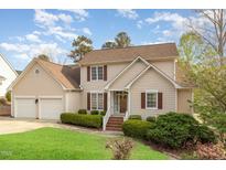 Charming two-story home featuring a two-car garage, lush lawn, and manicured shrubbery at 306 Neuse Ridge Dr, Clayton, NC 27527