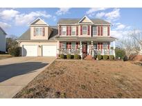 Charming two-story home boasts a welcoming front porch and well-manicured landscaping, and attached two car garage at 575 Crystal Spring Dr, Sanford, NC 27332