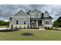 Beautiful two-story home with a manicured lawn and a welcoming brick and gray facade, exuding curb appeal at 90 Firefly Ln, Louisburg, NC 27549