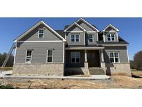 Beautiful two-story home features gray siding, brick accents, and a welcoming front porch at 90 Firefly Ln, Louisburg, NC 27549