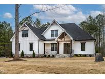 Beautiful two-story modern farmhouse-style home with a manicured lawn and inviting front porch at 3912 Cedar Knolls Dr, Youngsville, NC 27596