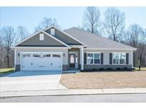 Single story home with gray siding, white garage doors, and landscaping at 46 Streamline Ct, Lillington, NC 27546