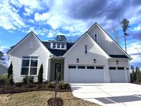Charming one-story white brick home with a two-car garage, a landscaped front yard and a blue sky at 200 Regency Ridge Dr, Holly Springs, NC 27540