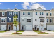 Charming new townhomes feature varied siding and attached garages with a sidewalk and small trees lining the street at 865 Parc Townes Dr # 4, Wendell, NC 27591