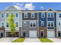 Charming townhome exterior showcasing varied siding, stone accents, and convenient attached garages in a vibrant community at 867 Parc Townes Dr # 3, Wendell, NC 27591