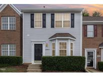 Two-story townhome with brick and siding exterior, landscaping, and a charming front entrance at 10947 Pendragon Pl, Raleigh, NC 27614
