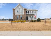 Two-story home with gray siding, brick accents, and a landscaped yard at 147 E Wellesley Dr, Clayton, NC 27520