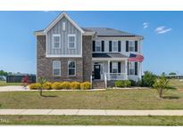 Beautiful two-story home with brick and vinyl siding, complemented by a well-manicured lawn and an inviting front porch at 147 E Wellesley Dr, Clayton, NC 27520
