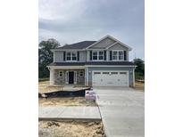 Charming two-story home with a stone-accented facade and an attached two-car garage and freshly poured driveway at 203 Lake Edge Dr, Lillington, NC 27546