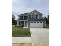 Two story home featuring a two car garage, stone accents, manicured lawn and charming curb appeal at 217 Lake Edge Dr, Lillington, NC 27546