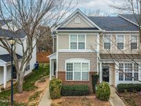 Two-story townhome with brick and siding exterior, landscaping, and a sidewalk at 5734 Corbon Crest Ln, Raleigh, NC 27612