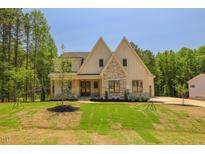 An exterior shot of a beautifully designed home with a lush green lawn and wooded surroundings at 1116 Delilia Ln, Wake Forest, NC 27587