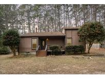 Brown ranch home with wood siding, steps to covered porch, and landscaping at 129 Lady Bug Ln, Chapel Hill, NC 27516
