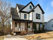 Two-story farmhouse style home with black accents and a wrap-around porch at 1317 Fay St, Durham, NC 27701